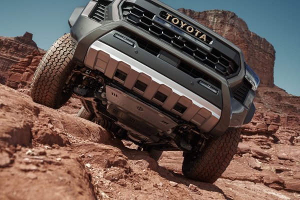 Photo taken at a low angle of a gray Toyota truck peaking over a desert rock